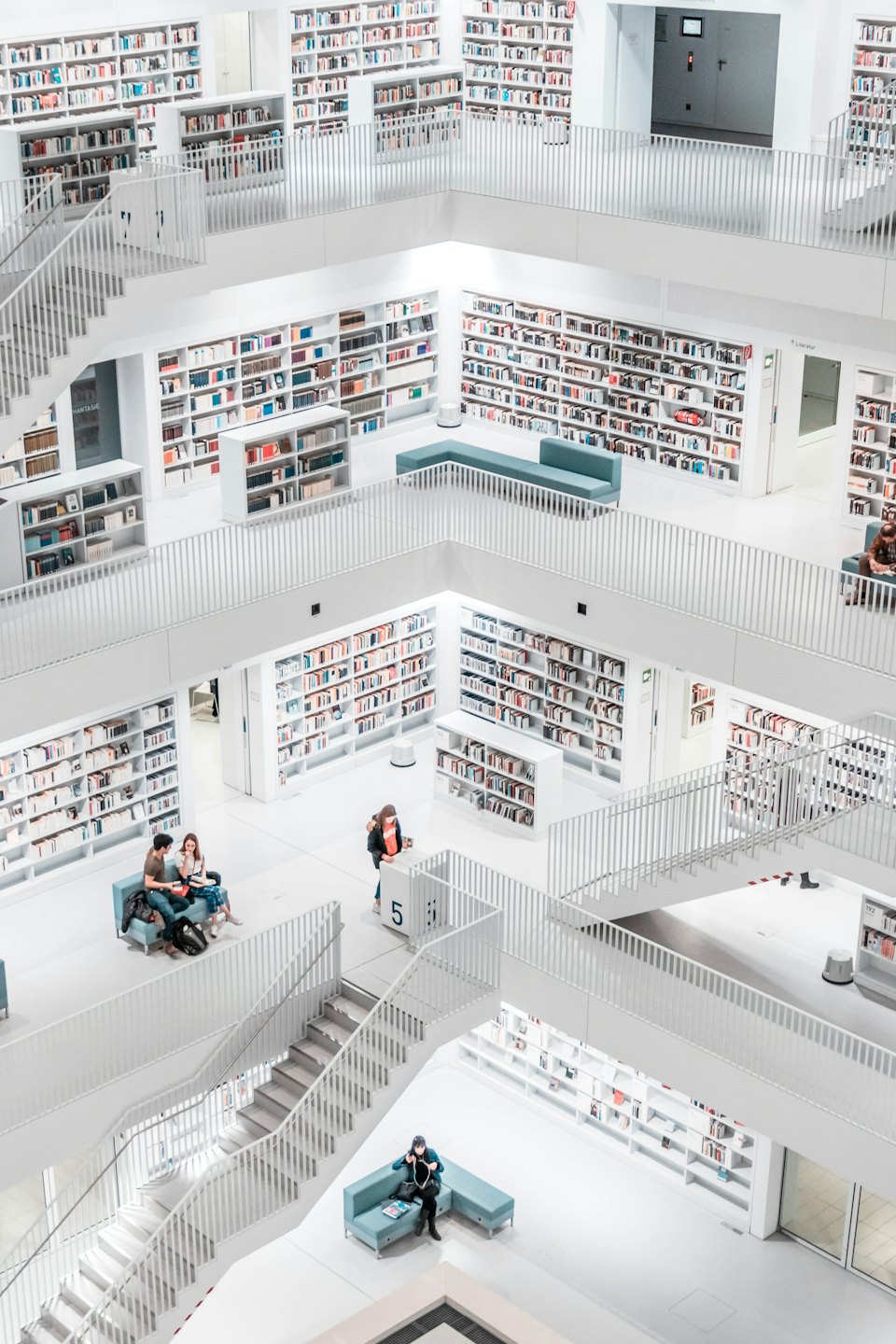 Modern library interior with patrons browsing colorful books.